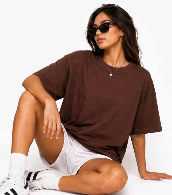 Woman wearing oversized brown cotton t-shirt with white shorts and sneakers, casual streetwear outfit