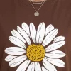 Woman wearing oversized brown daisy print t-shirt with white denim shorts, casual streetwear style