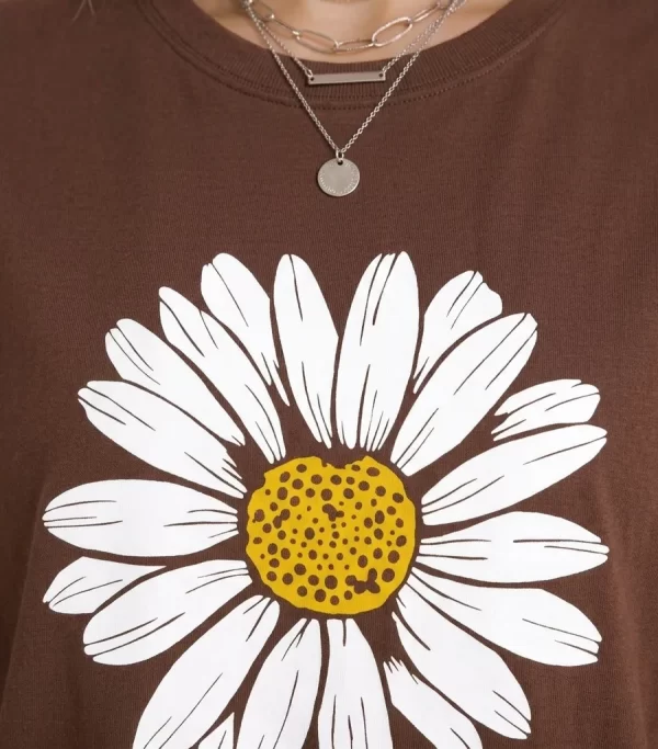 Woman wearing oversized brown daisy print t-shirt with white denim shorts, casual streetwear style