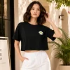 Woman wearing black cropped t-shirt with cute daisy sunglasses graphic design, paired with white pants