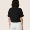Woman wearing black cropped t-shirt with cute daisy sunglasses graphic design, paired with white pants