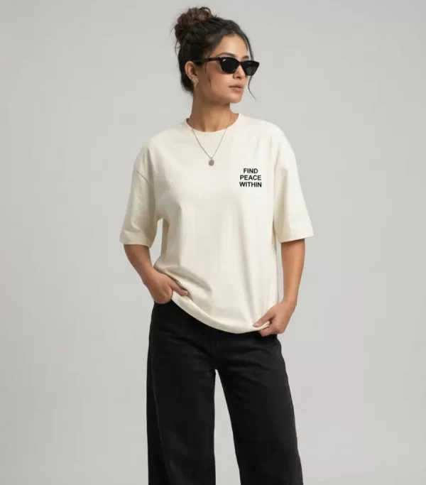 Front view: "Woman wearing beige oversized t-shirt with 'Find Peace Within' text print, front view" Back view: "Woman wearing beige oversized t-shirt with Buddha silhouette sunset graphic print on back"