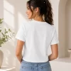 Woman wearing white cropped t-shirt with printed cat face "meow" graphic design and pink heart print, paired with blue jeans