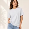 Woman wearing heather grey cotton t-shirt with blue denim jeans, casual everyday outfit