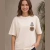 Woman wearing beige oversized t-shirt with Japanese ink-style mountain and red sun print on back, 'Find Peace Within' text with medallion graphic on front