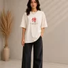 Woman wearing beige oversized Samurai graphic t-shirt with red Japanese kanji print, paired with black wide-leg jeans front and back view