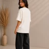 Woman wearing beige oversized Samurai graphic t-shirt with red Japanese kanji print, paired with black wide-leg jeans – front and back view