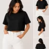 Woman wearing black oversized cropped t-shirt with boxy fit, paired with white jeans
