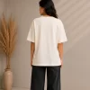 Woman wearing beige oversized Samurai graphic t-shirt with red Japanese kanji print, paired with black wide-leg jeans front and back view