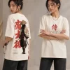 Woman wearing beige oversized t-shirt with samurai warrior illustration and red Japanese kanji print on back, 'SAMURAI' text print on front, styled with black wide-leg jeans
