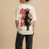 Woman wearing beige oversized t-shirt with samurai warrior illustration and red Japanese kanji print on back, 'SAMURAI' text print on front, styled with black wide-leg jeans