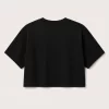 Woman wearing black oversized cropped t-shirt with boxy fit, paired with white jeans