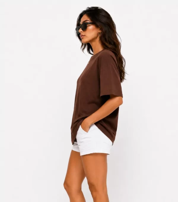 Woman wearing oversized brown cotton t-shirt with white shorts and sneakers, casual streetwear outfit