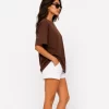 Woman wearing oversized brown cotton t-shirt with white shorts and sneakers, casual streetwear outfit