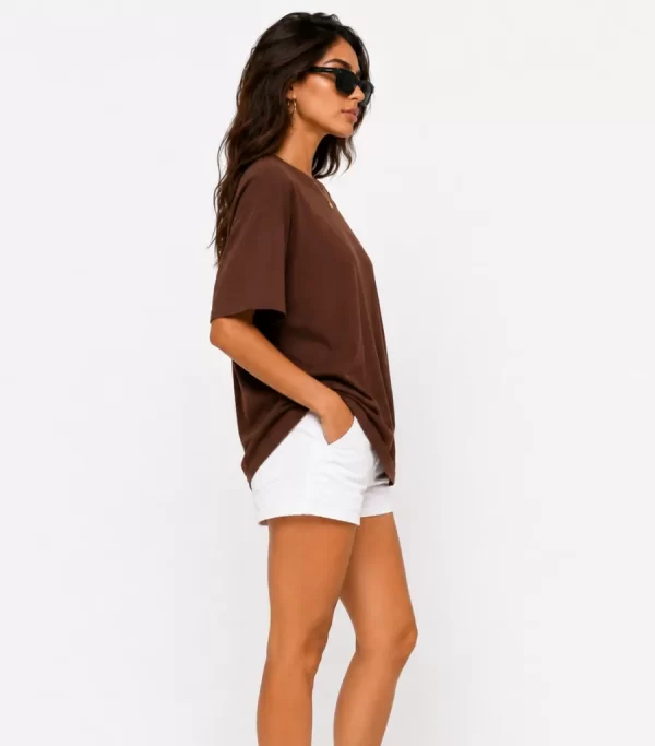 Woman wearing oversized brown cotton t-shirt with white shorts and sneakers, casual streetwear outfit