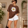 Woman wearing oversized brown daisy print t-shirt with white denim shorts, casual streetwear style