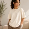 "Woman wearing oversized cream cotton t-shirt with brown cargo pants, minimal casual outfit"