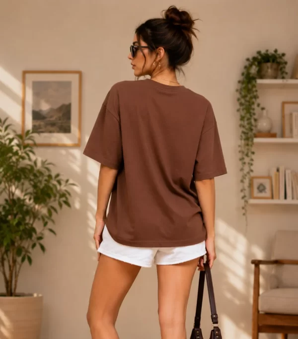 Woman wearing oversized brown daisy print t-shirt with white denim shorts, casual streetwear style