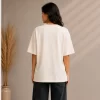 Image 1 (Front View) Women's oversized white graphic printed cotton t-shirt front view with abstract colorful face print. Image 2 (Side View) Women's white oversized graphic t-shirt side profile featuring modern abstract print and relaxed fit. Image 3 (Back View) Women's oversized white cotton t-shirt back view showing plain design with half sleeves and relaxed fit. Image 4 (Angled View) Women's oversized white graphic print t-shirt angled view with premium cotton fabric and casual streetwear style.